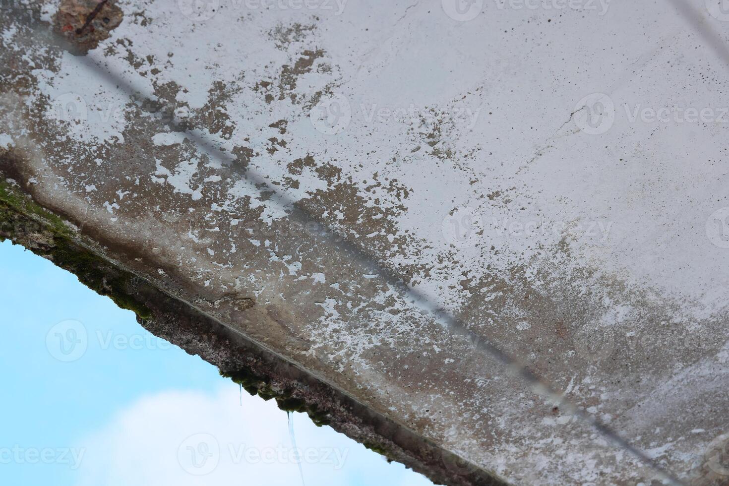 An aged, weathered concrete structure stands prominently against a clear blue sky above photo