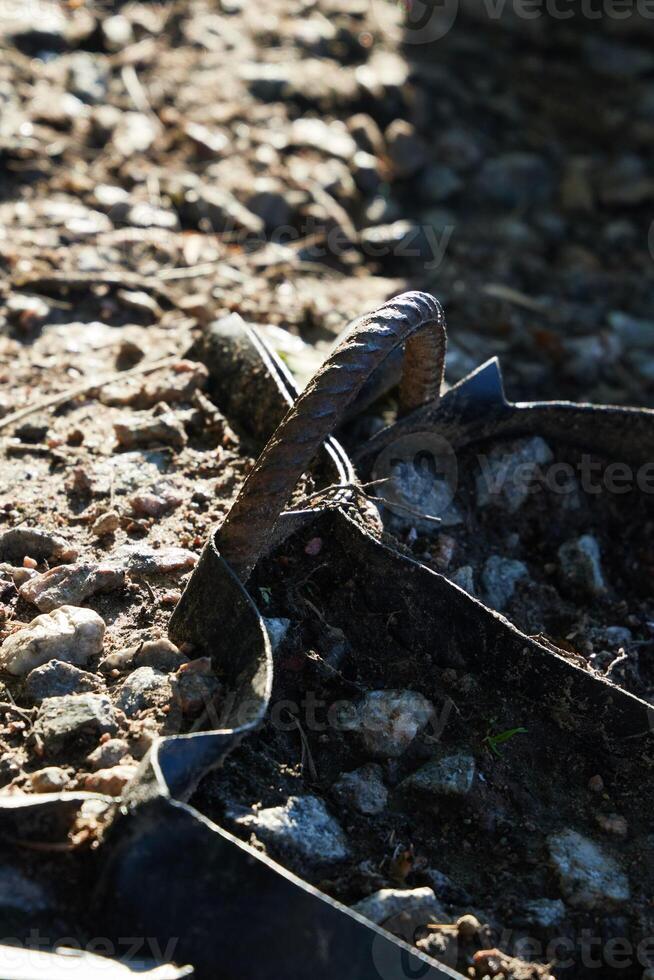 A Rusty Nail is Deeply Embedded in the Ground Amidst the Natural Landscape Around It photo