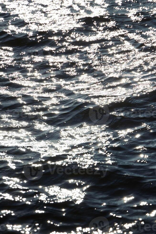 The shimmering water surface dances with sunlight reflections creating a tranquil scene photo