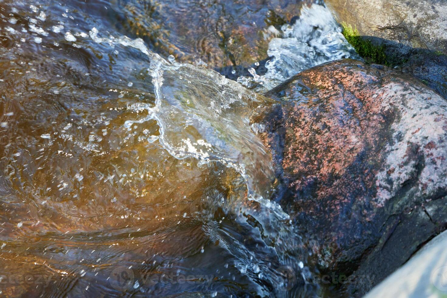 The captivating sight of flowing water gracefully cascading over rocks in a natural stream photo