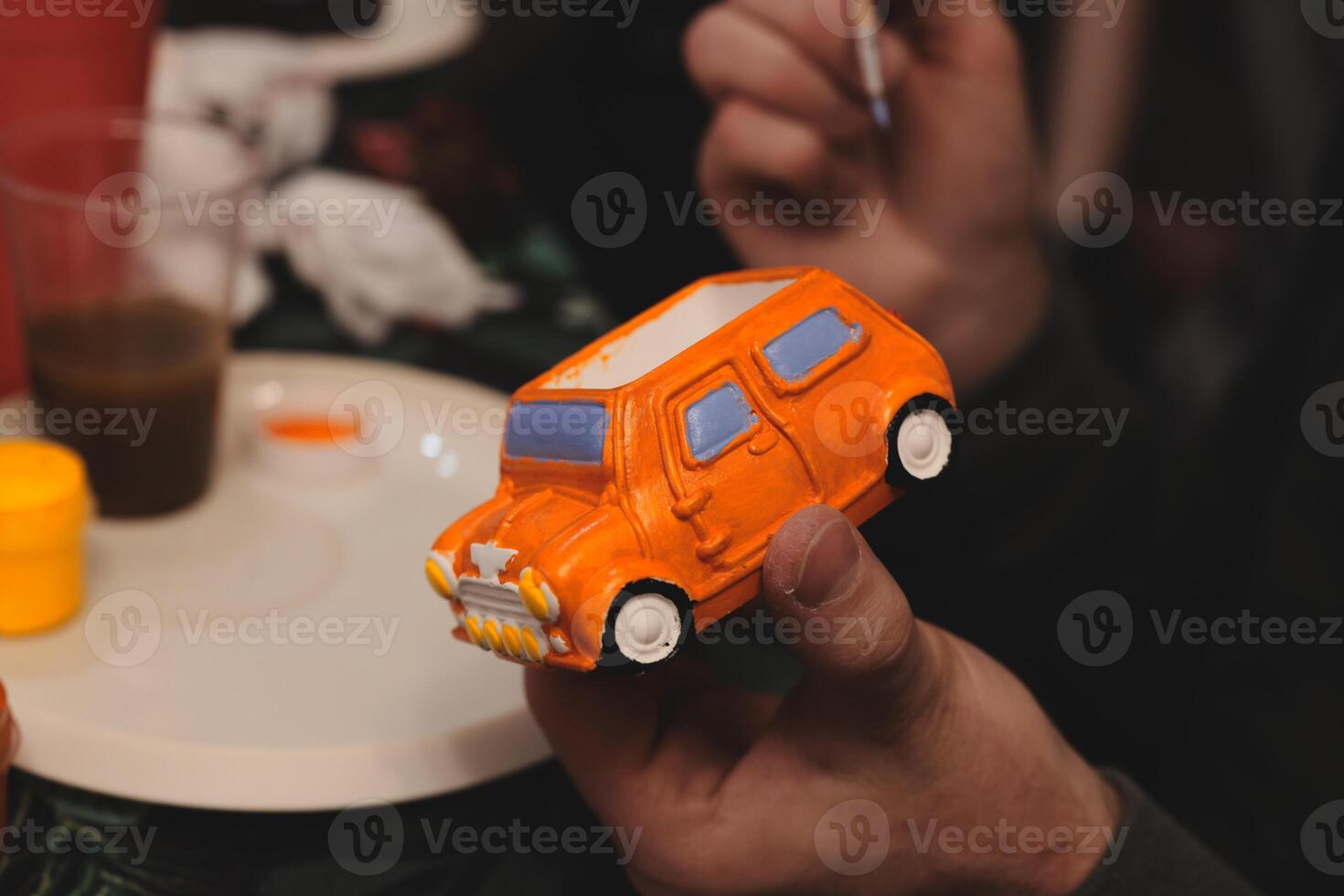 A Creative Painting Activity Featuring a Miniature Model of an Orange Car Design photo