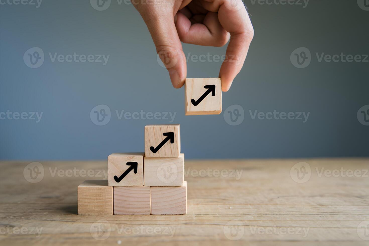 Hand balances arrow topped block, symbolizing progress, against calm blue gradient photo