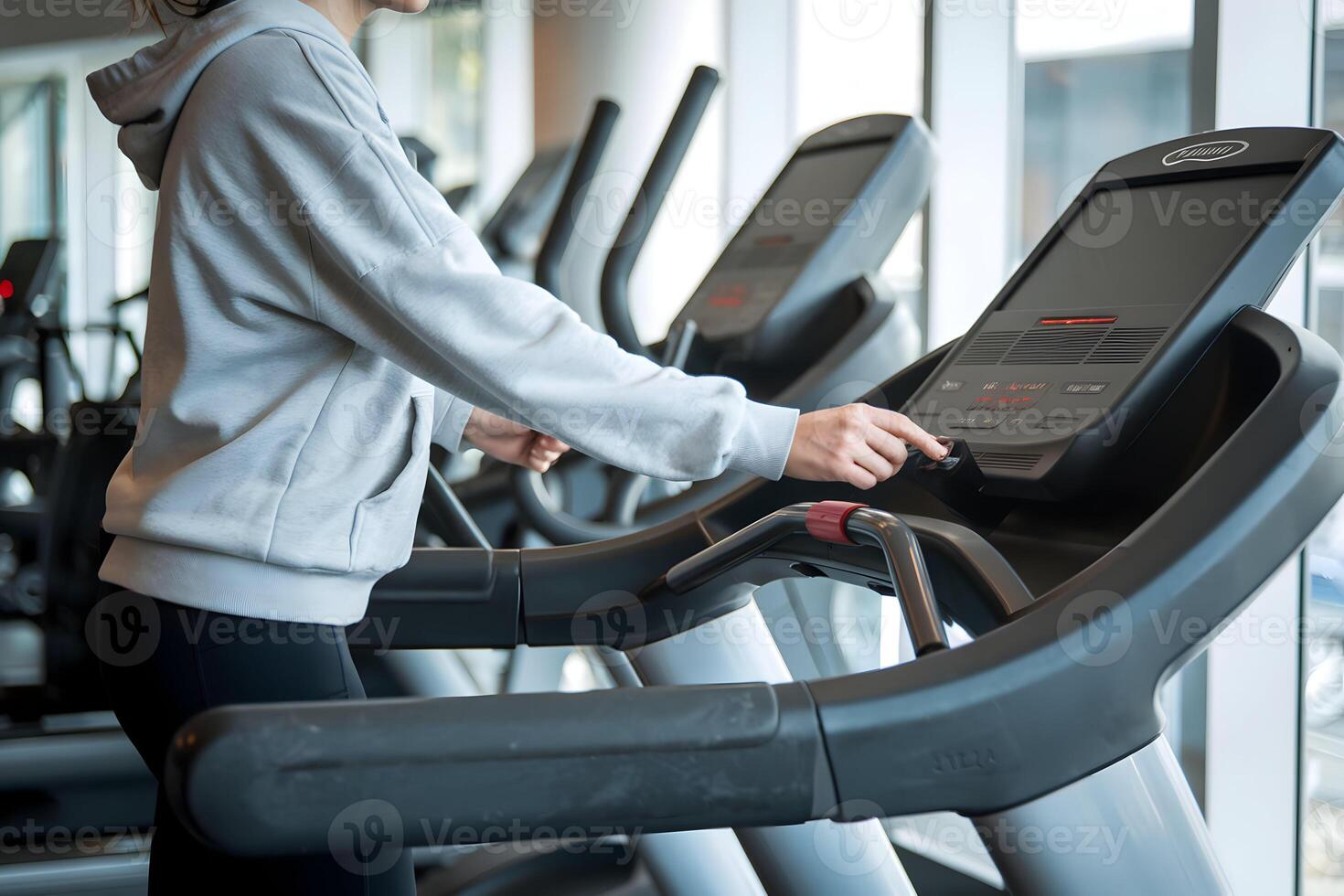 Person on treadmill in modern gym, adjusting controls, casual fitness vibe photo