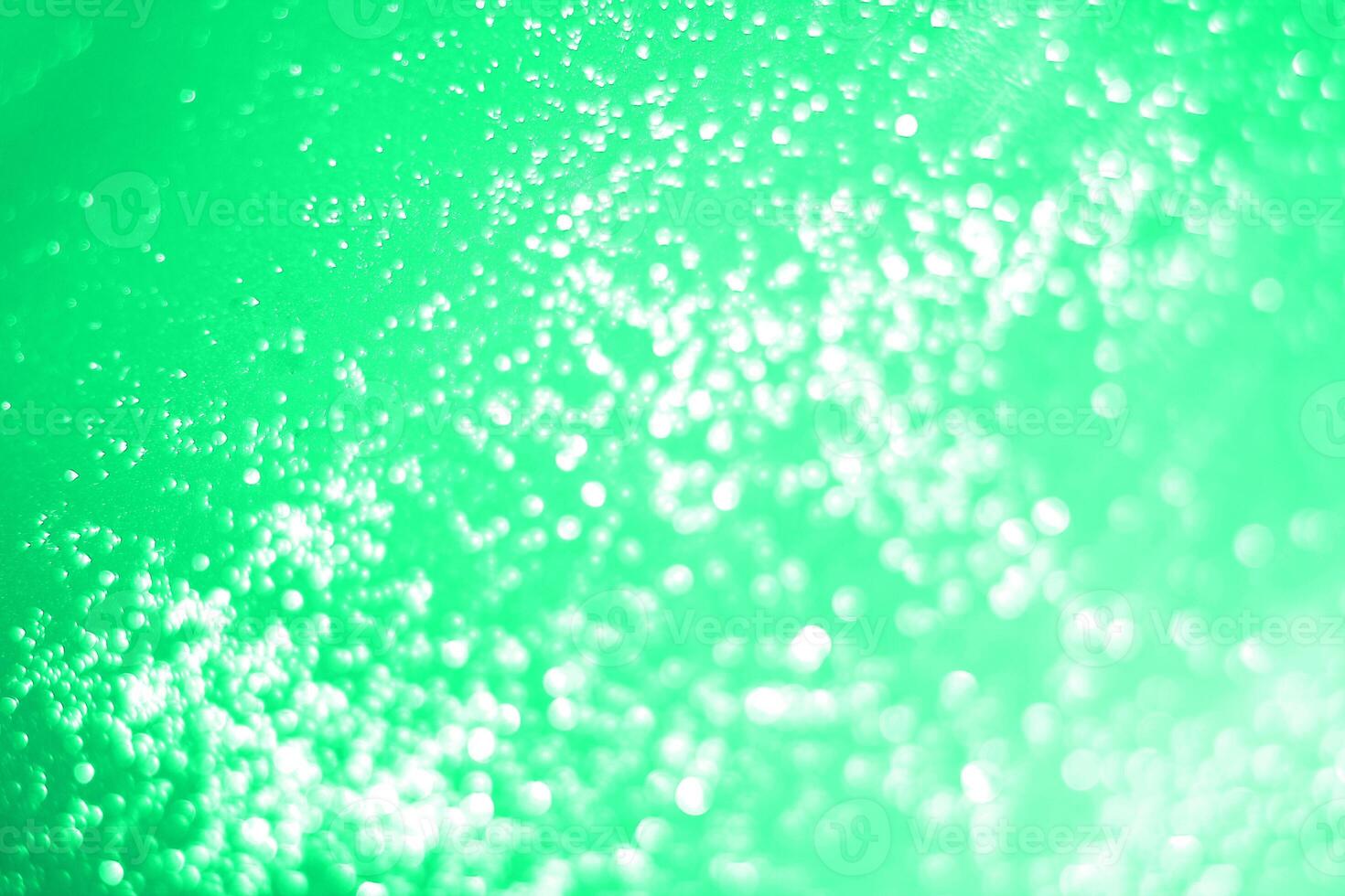 A green light is shining on a surface with bubbles photo
