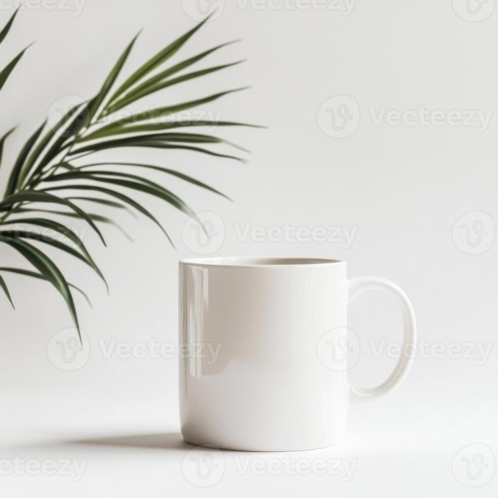 Plain white mug next to green leaf on light background creates a minimalist feel in a cozy setting photo