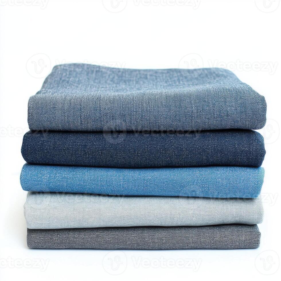 Stacked fabric pieces in varying shades of blue and gray on a white background showcase textures and colors photo