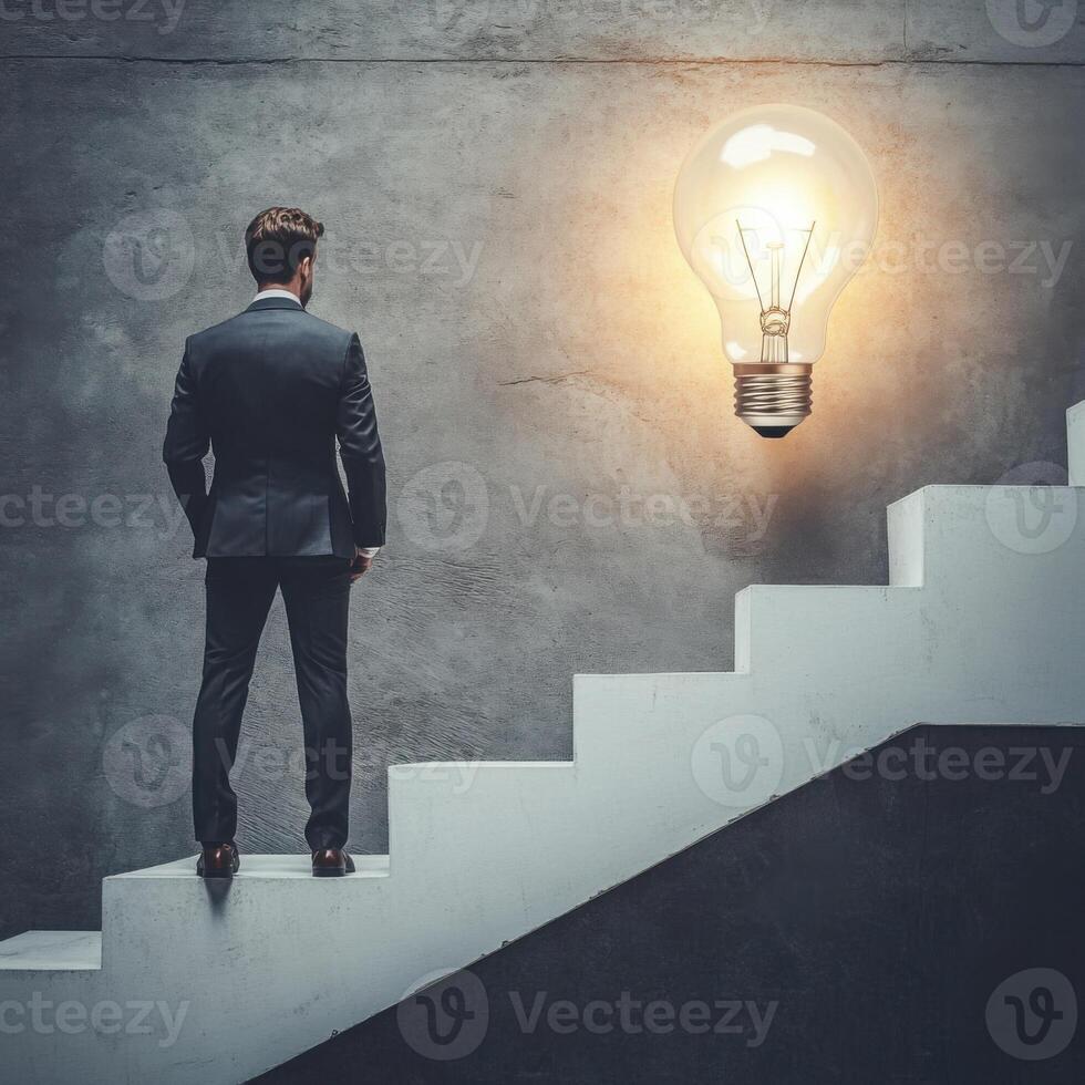 Man in a suit standing at the bottom of stairs looking up at a large light bulb on the wall in a modern setting photo