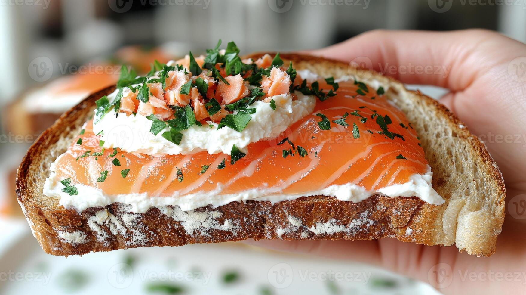 A hand holds a crafted open-faced sandwich with smoked salmon, cream cheese, and herbs photo