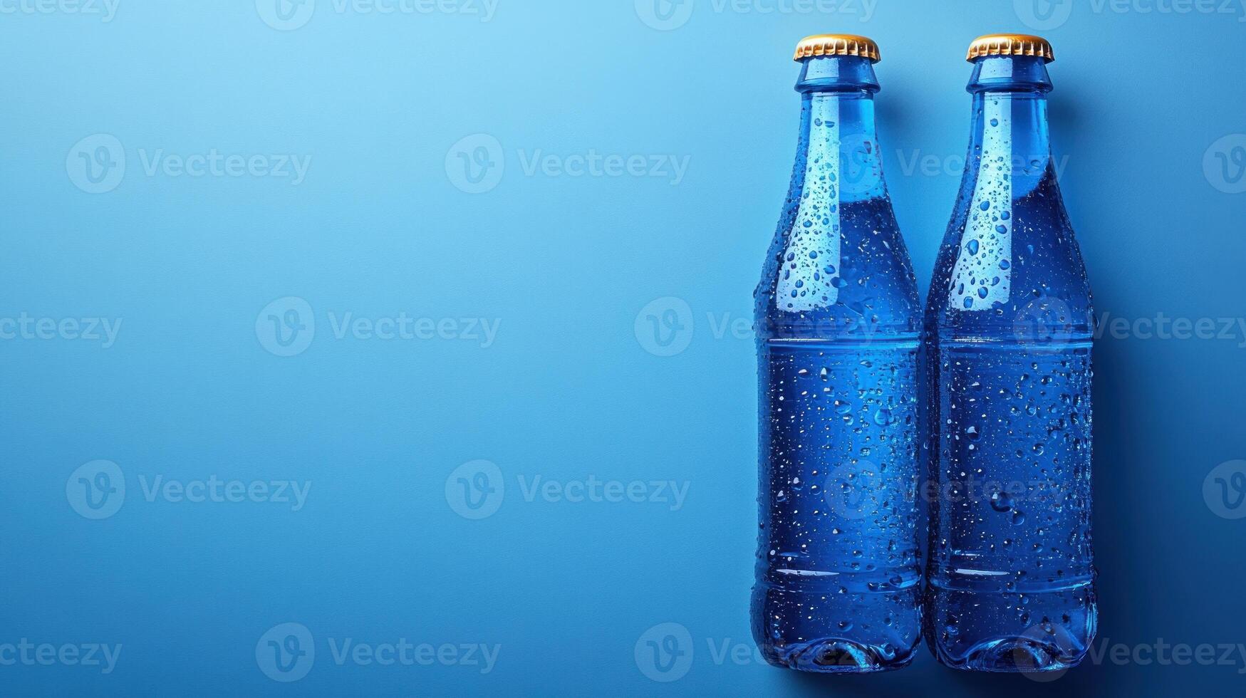 Two glass bottles glisten with condensation against a bright blue background, evoking summer vibes photo