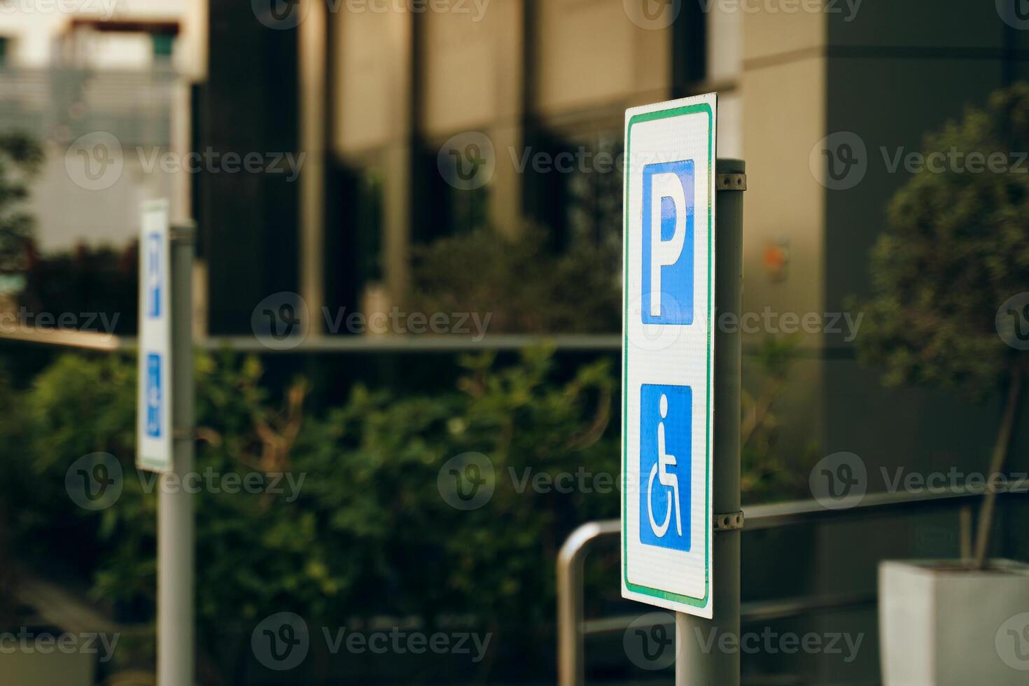 A street sign in electric blue font marks the reserved handicapped parking spot in front of the building on the grassy city road photo