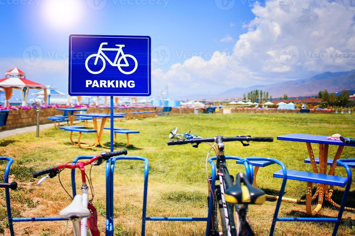 A bicycle is parked in a land lot with lush green grass under a cloudy sky, surrounded by nature and asphalt landscape photo