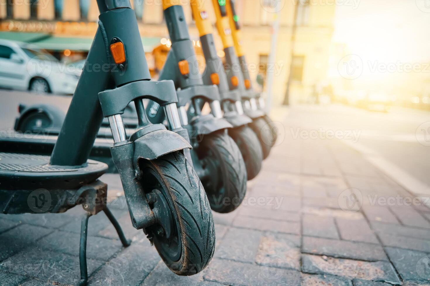 A line of motor vehicles with Automotive tires are parked on the sidewalk, their wheels made of synthetic rubber with treads. Some have bumpers and automotive lighting photo