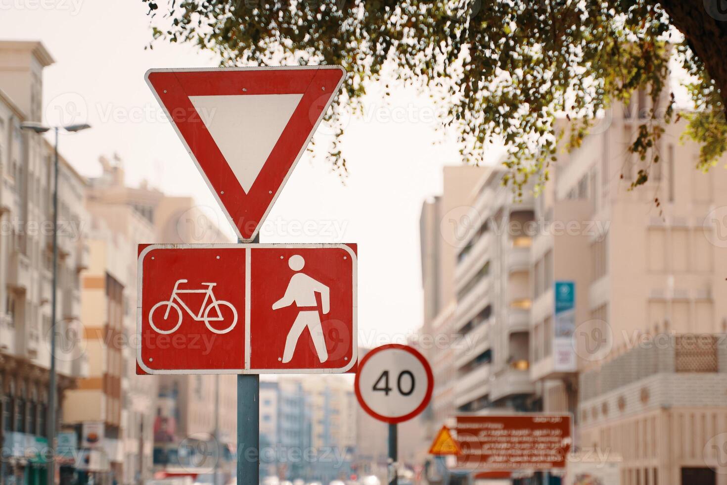 A red traffic sign in the neighbourhood features a bicycle and pedestrian symbol, promoting safety and shared use of the road infrastructure during daytime photo