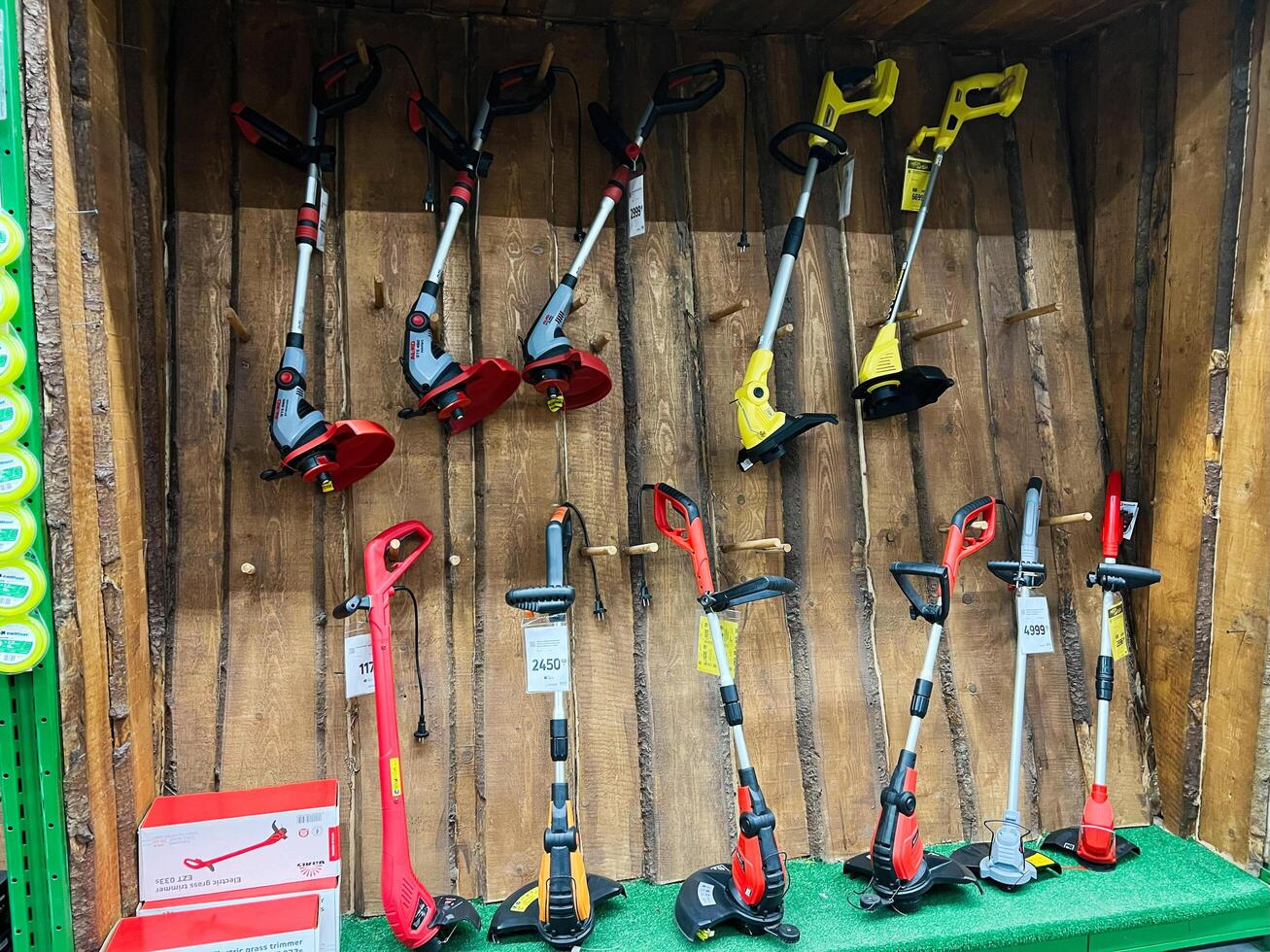 Kyiv, Ukraine - January 03, 2025 Display of electric grass trimmers in a store with wooden wall background photo