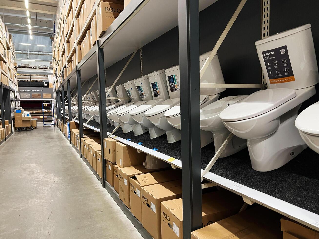 Kyiv, Ukraine - January 03, 2025 Row of toilet displays in a warehouse store with stacked boxes photo