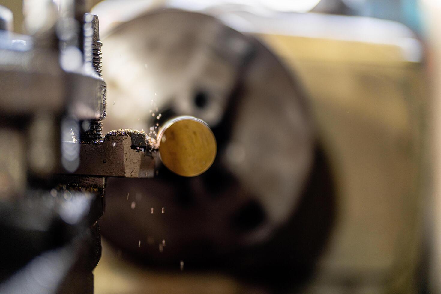 The operation of a metal lathe is captured in detail, featuring a steel column rolling during precision machining. photo