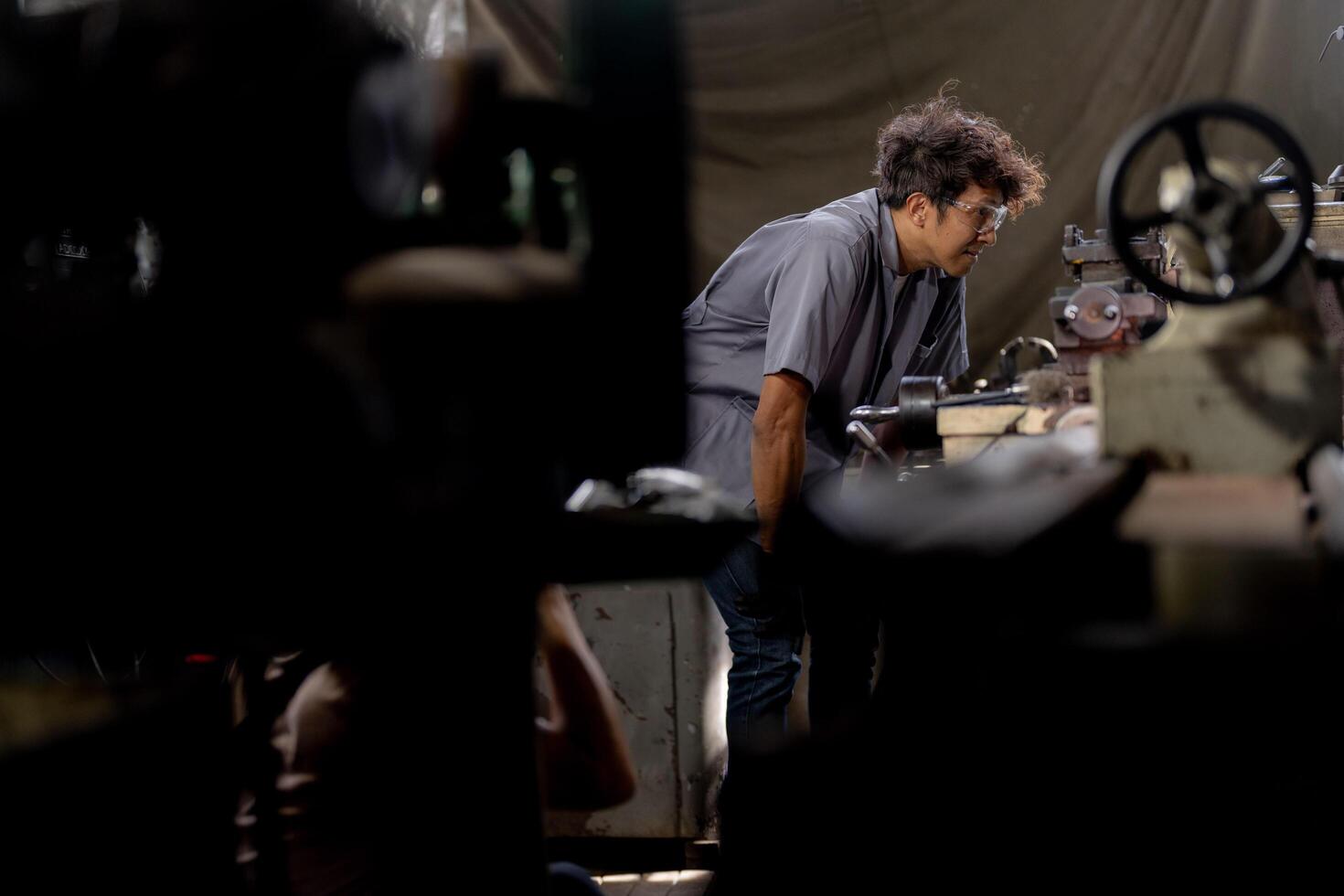 A close up reveals the detailed mechanics of a lathe machine as a steel column undergoes processing. photo