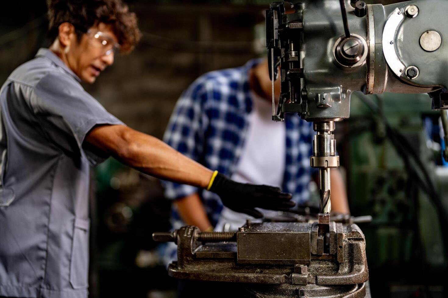 A close up view showcases the steel column rolling within a metal lathe machine during surface refinement. photo