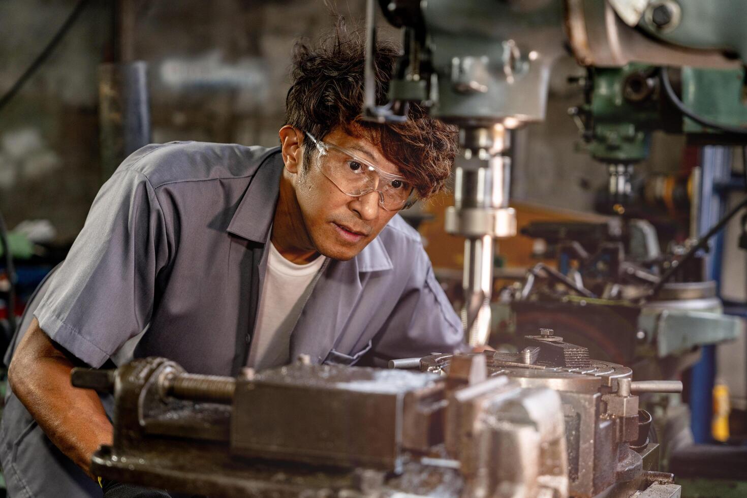 Sparks illuminate the scene as a worker grinds steel surfaces in a factory. photo