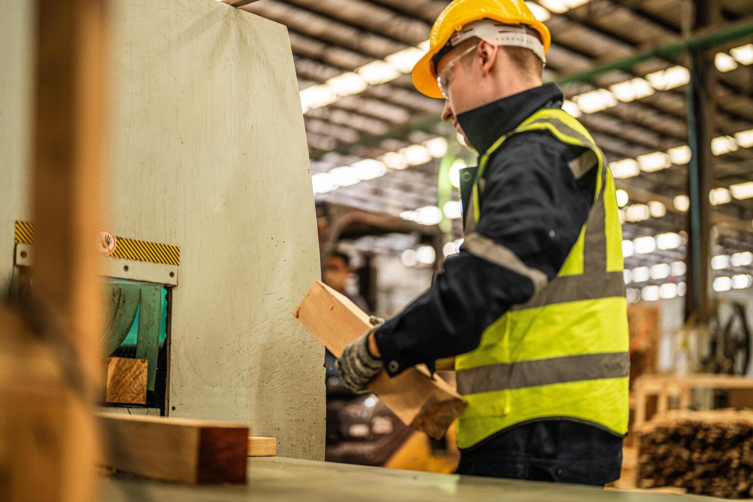 In an industrial warehouse, a man focuses on cleaning timber to maintain its quality. photo