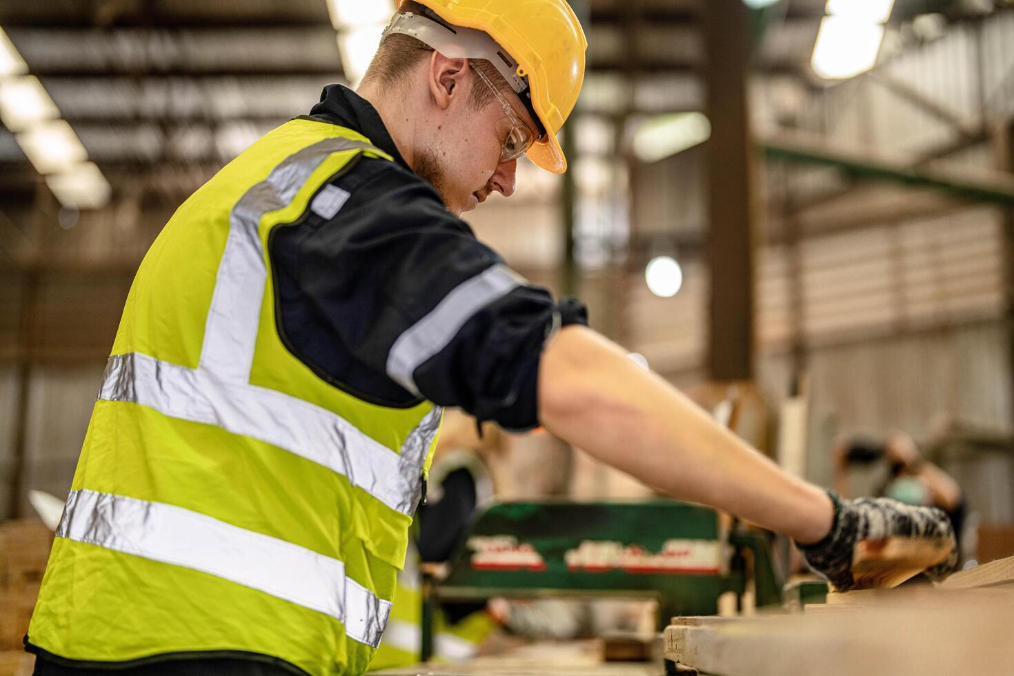 Workers in safety gear inspect wooden items in a well-lit manufacturing facility. photo