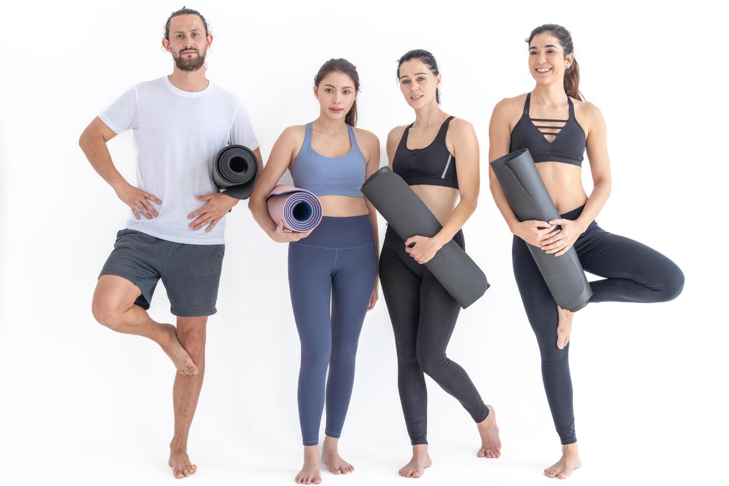 Group of happy sporty w ome n and guy wearing body stylish sportswear holding personal carpets leaned on a white background. waiting for yoga class or body weight class. healthy lifestyle and wellness photo