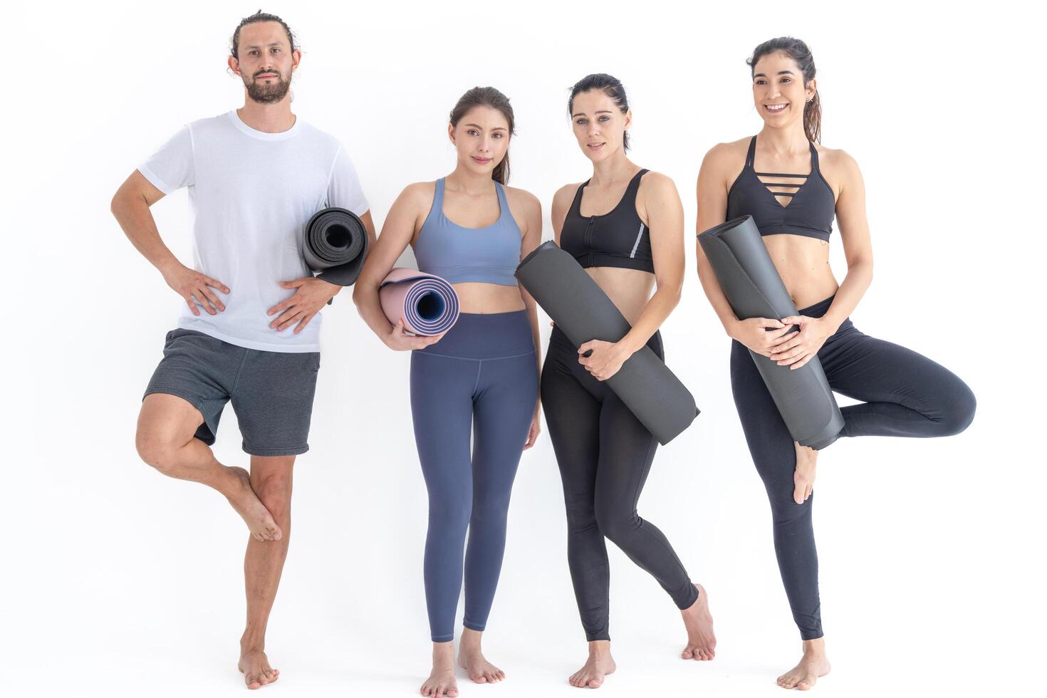 Group of happy sporty w o men and guy wearing body stylish sportswear holding personal carpets leaned on a white background. waiting for yoga class or body weight class. healthy lifestyle and wellness photo
