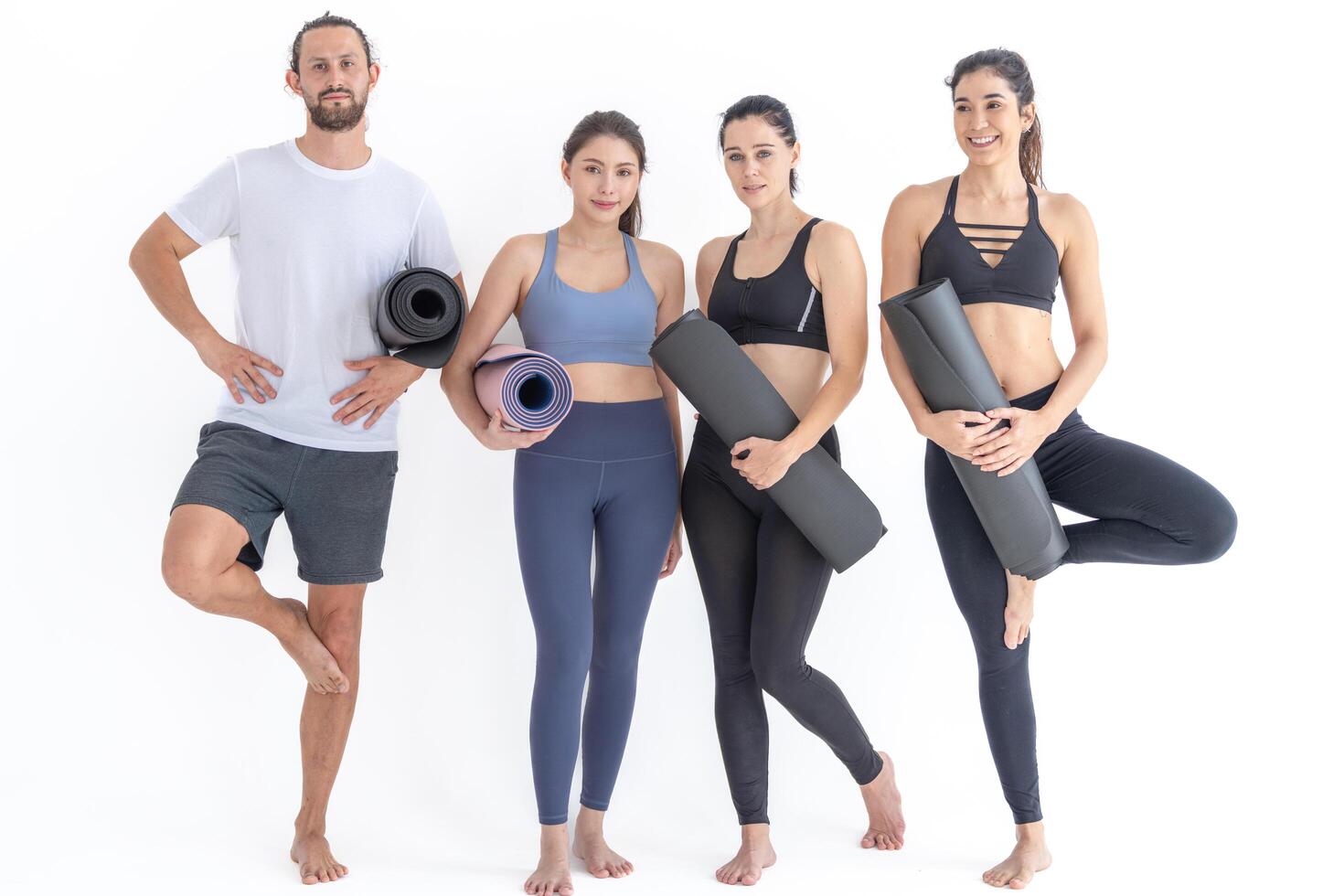 Group of happ y sporty women and guy wearing body stylish sportswear holding personal carpets leaned on a white background. waiting for yoga class or body weight class. healthy lifestyle and wellness photo