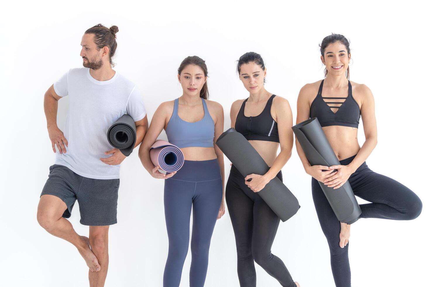 Group of ha ppy sporty women and guy wearing body stylish sportswear holding personal carpets leaned on a white background. waiting for yoga class or body weight class. healthy lifestyle and wellness photo