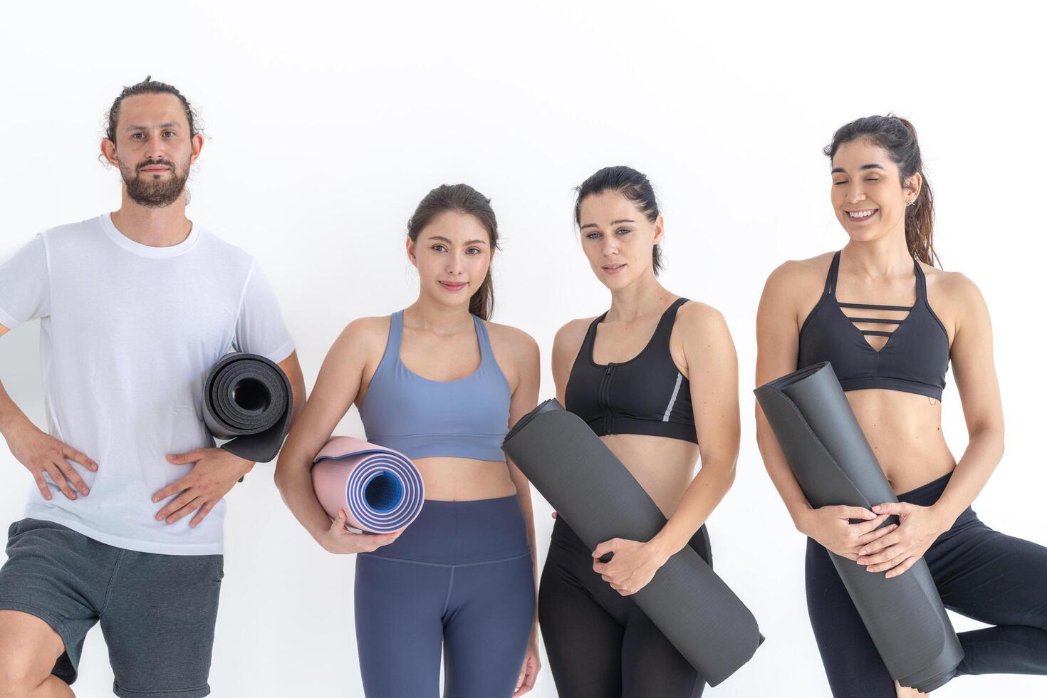 Group of happy sporty wome n and guy wearing body stylish sportswear holding personal carpets leaned on a white background. waiting for yoga class or body weight class. healthy lifestyle and wellness photo