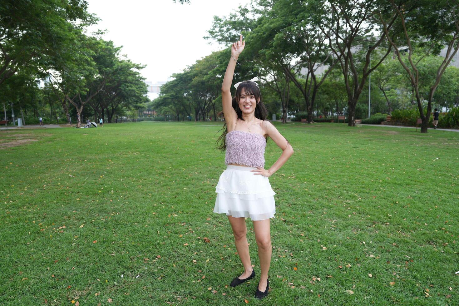 A joyful young woman dances in harmony indoors, with a dec orative brick wall and lush plants enhancing the harmony and peace. photo
