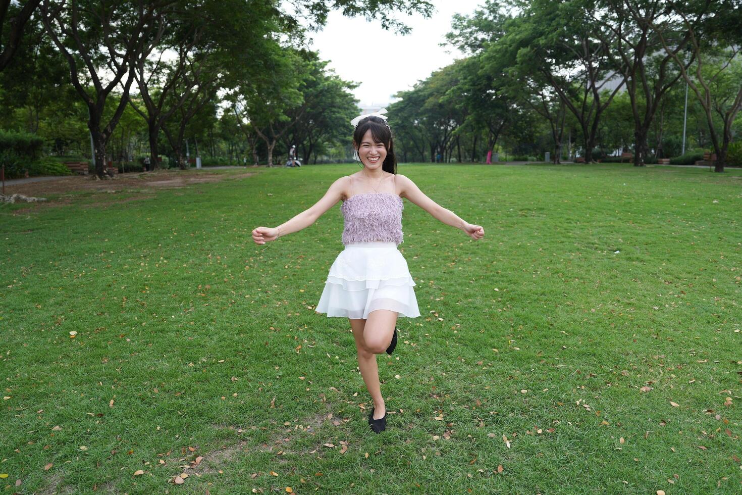 A young woman da nces joyfully in a serene indoor space, framed by a decorative brick wall and a scenic view, embodying harmony and peace. photo
