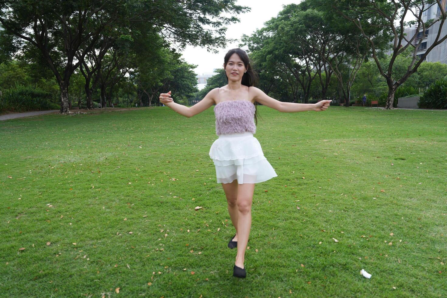 A joyful young woman dances in harmony indoors, with large win dows and a scenic view enhancing the harmony and peace. photo