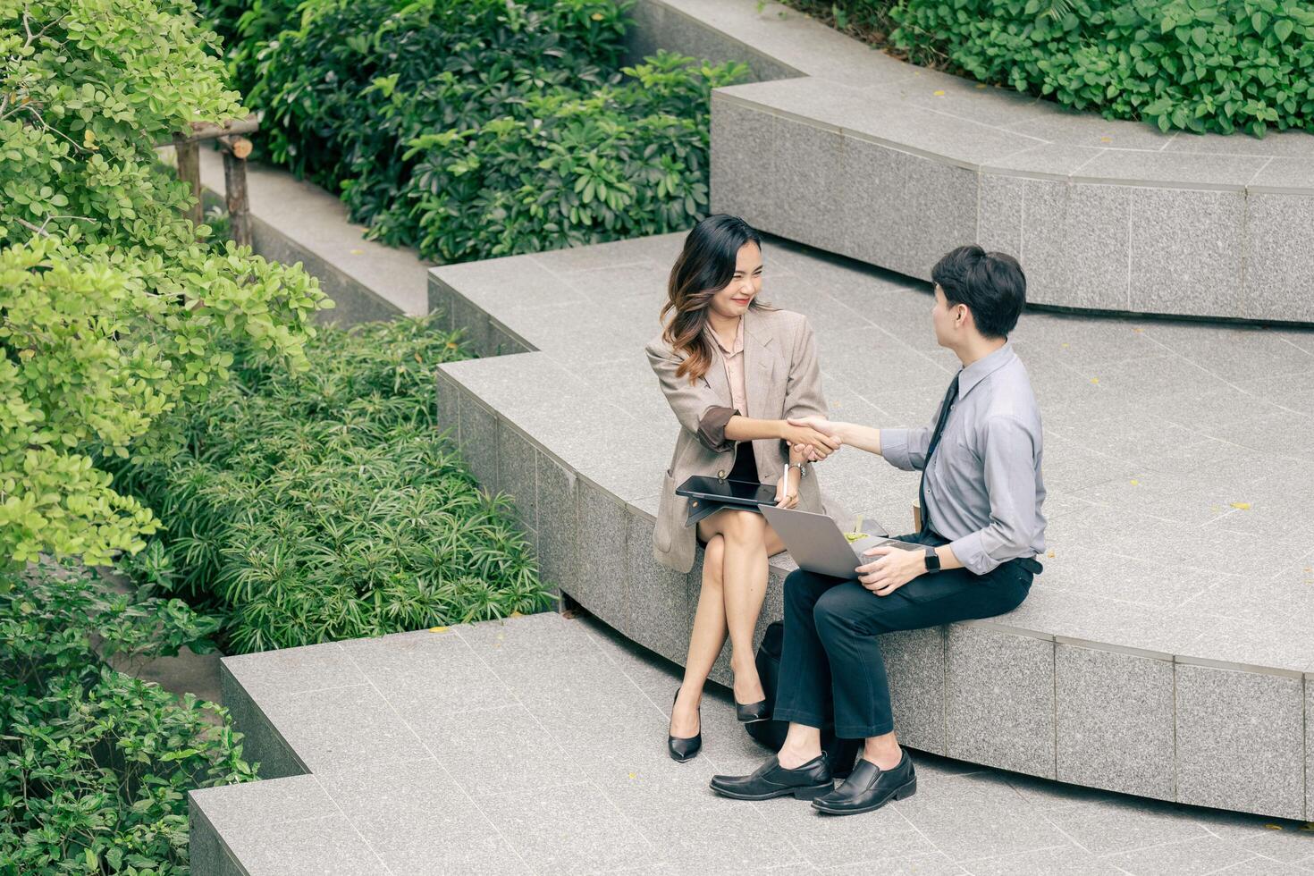 Two business man and woman shake hands outside a modern office building and successful business dealings. professionalism in a corporate setting. reflecting of collaboration and strategic planning. photo