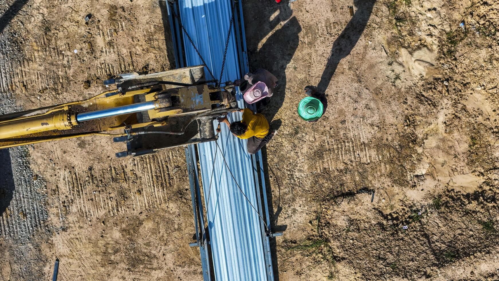 Aerial view of workers pla cing long metal sheets onto a building framework with the aid of heavy machinery, highlighting precision, teamwork, and modern techniques in construction projects. photo