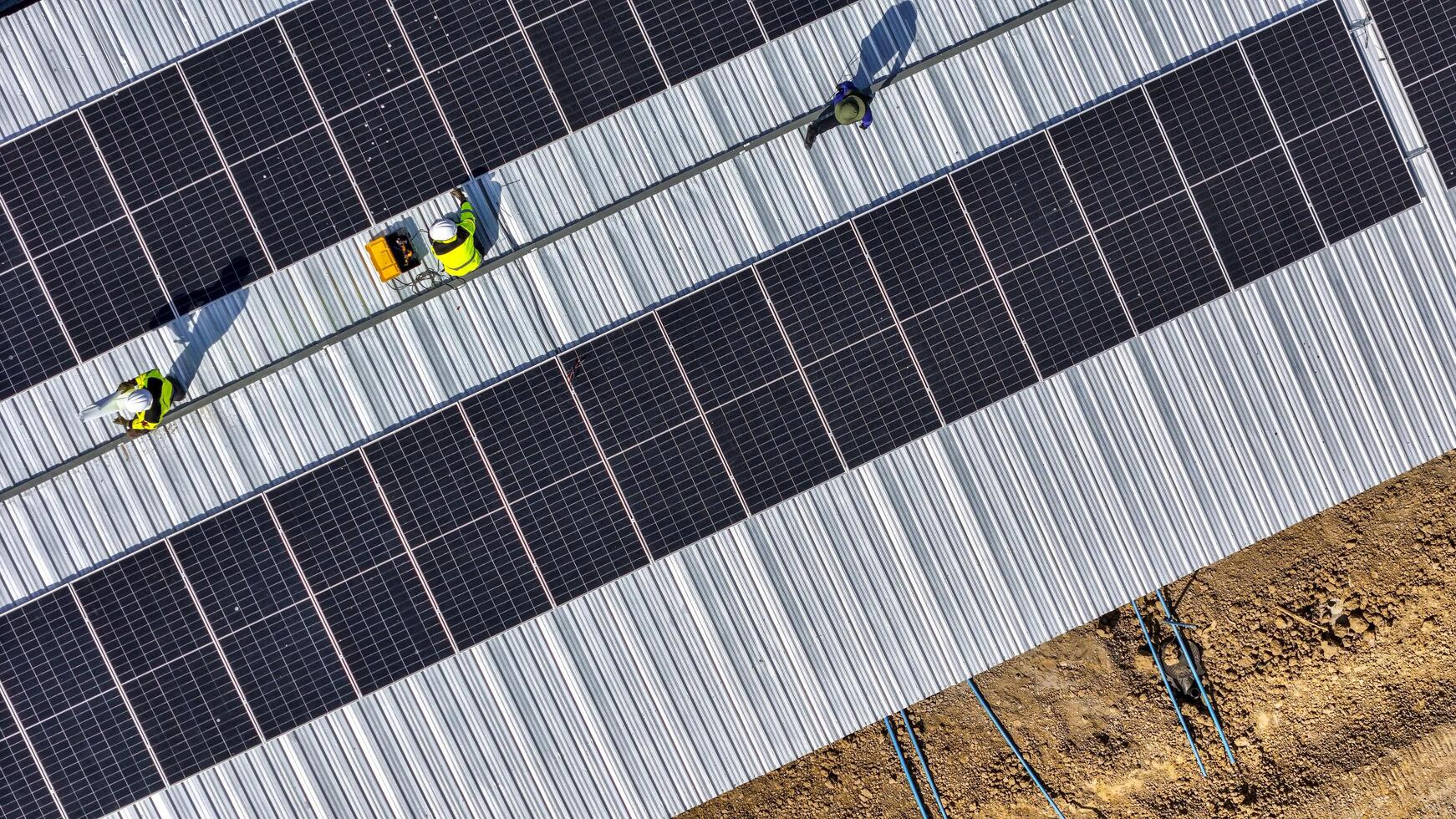 Two workers in safety gear i nstalling solar panels on a rooftop, highlighting renewable energy, sustainability, and the integration of skilled labor in setting up efficient solar power systems. photo