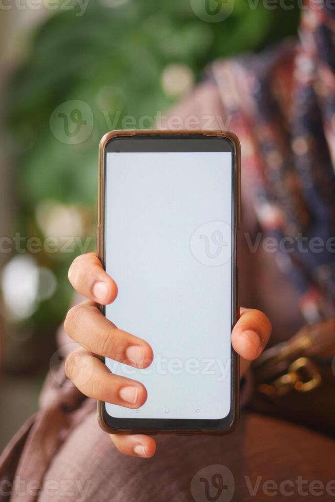 Person Holding Smartphone with Blank Screen in Bright and Natural Setting photo