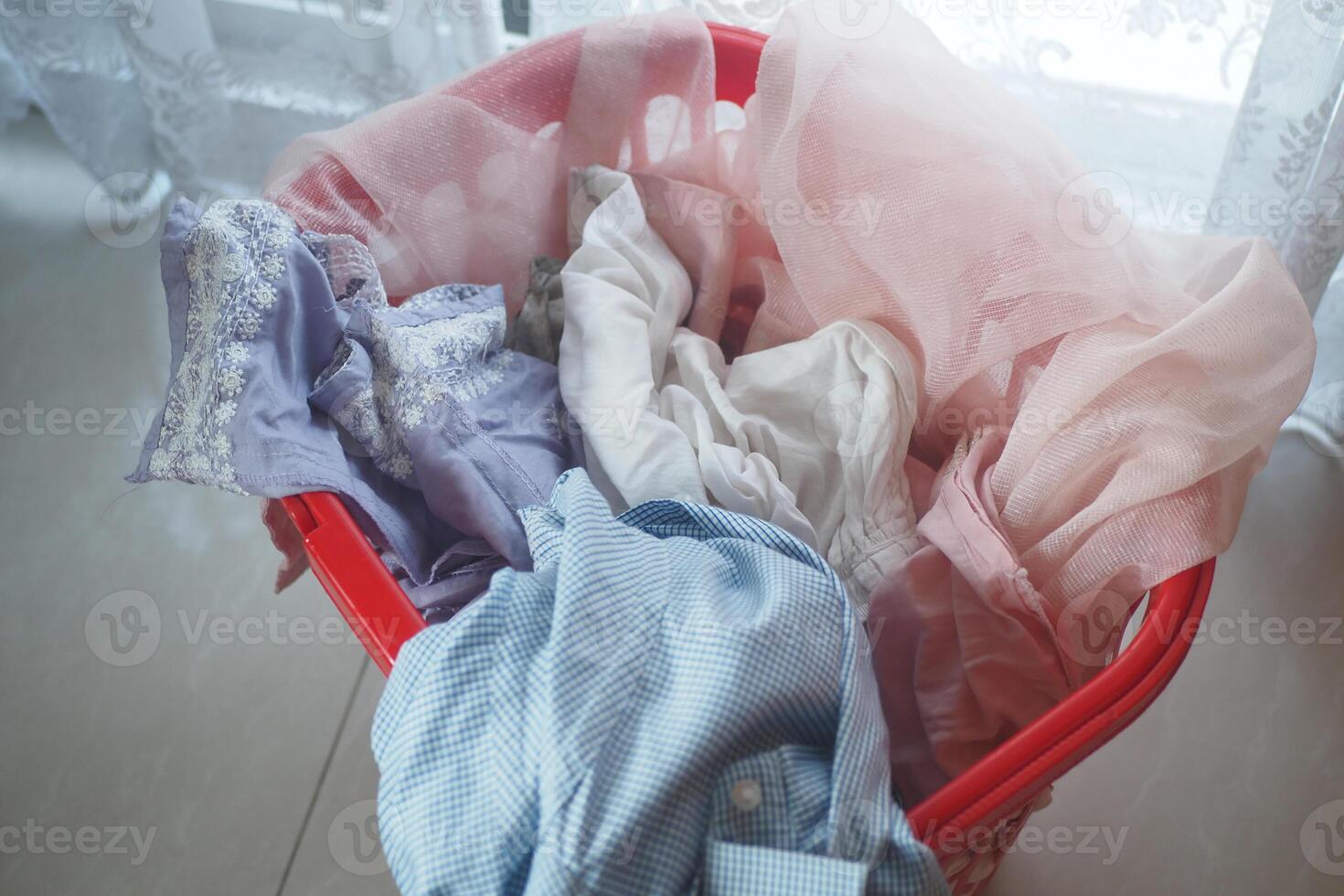 Colorful laundry in a red basket by a window brightens the space photo