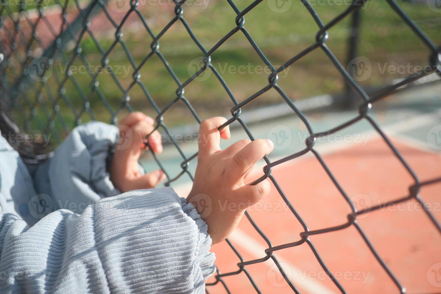 A Childs Small Hands Firmly Grasping a Chainlink Fence in Clear Focus photo