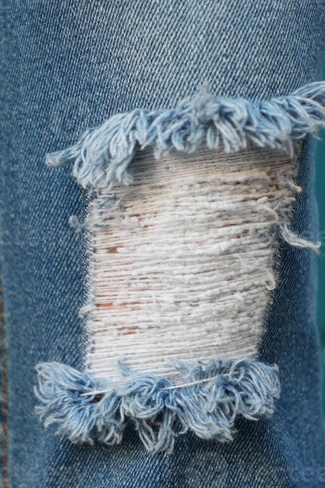 blue jean texture with a hole and ripped threads showing photo