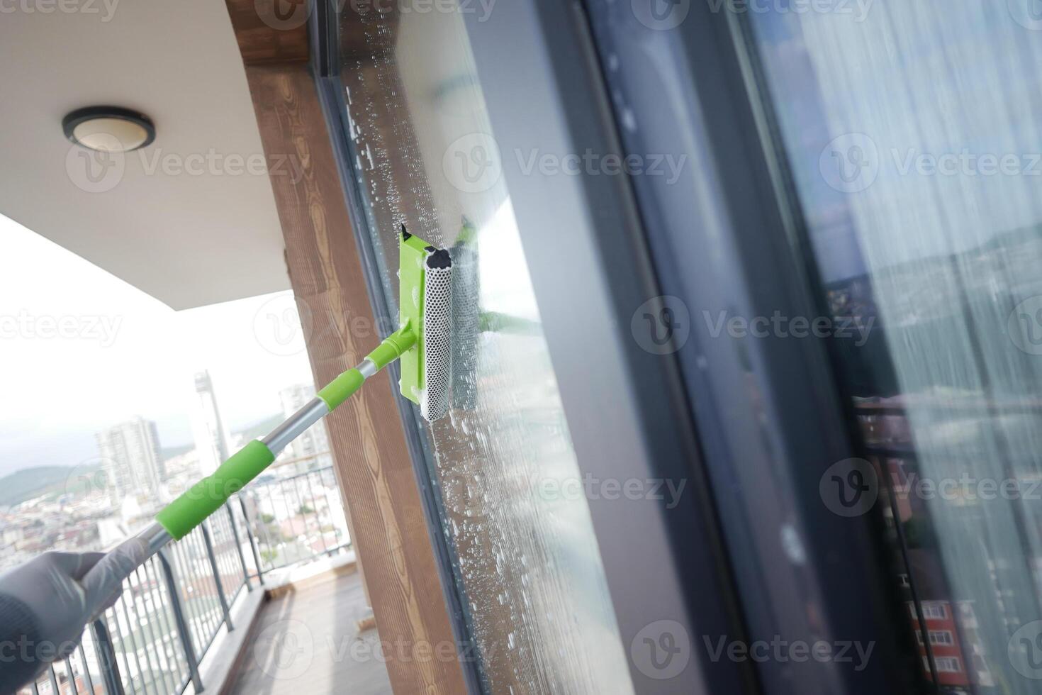 Rubber squeegee cleans a soaped window. photo