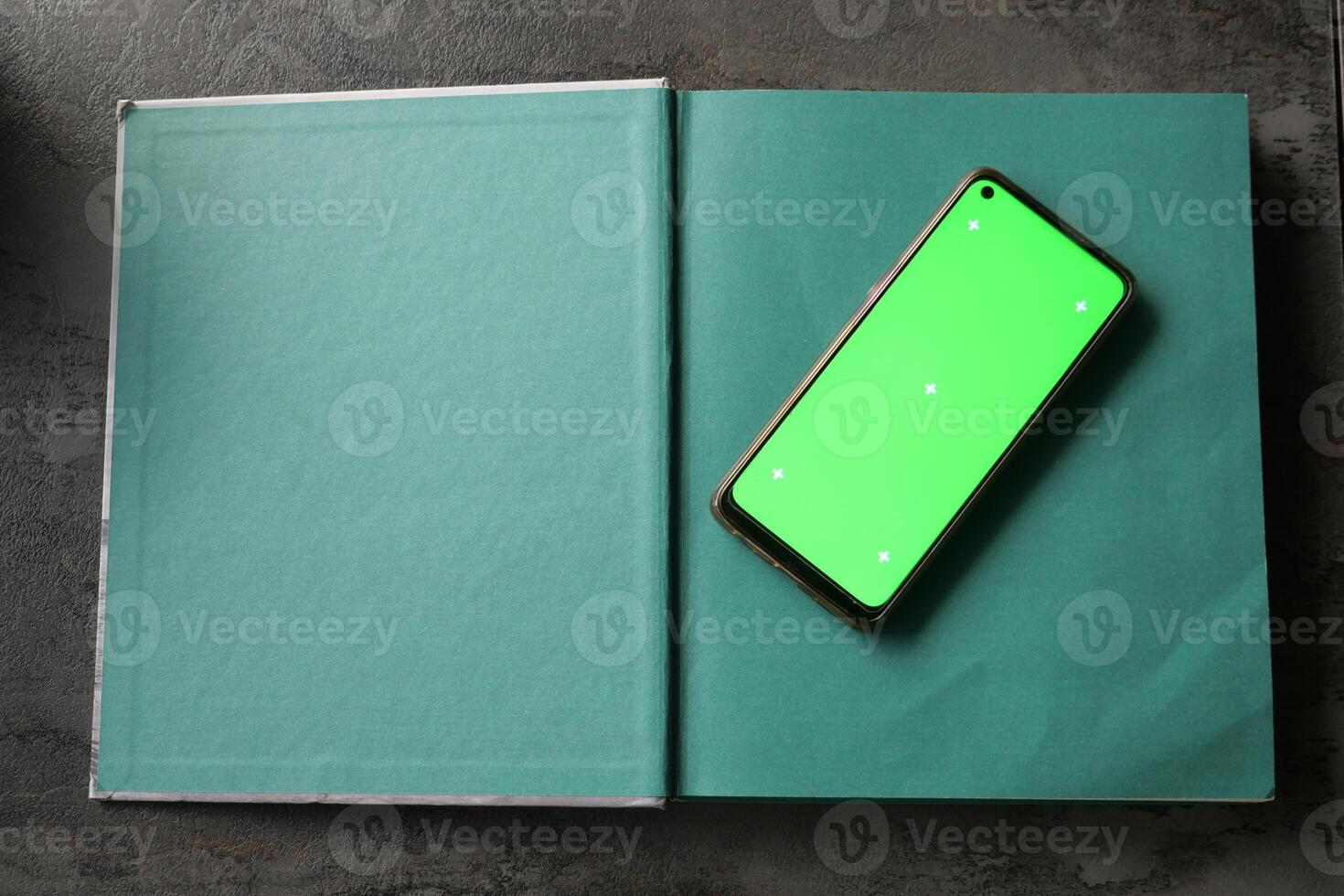 A Green Phone resting on an Open Book An Excellent Mockup for Digital Content photo