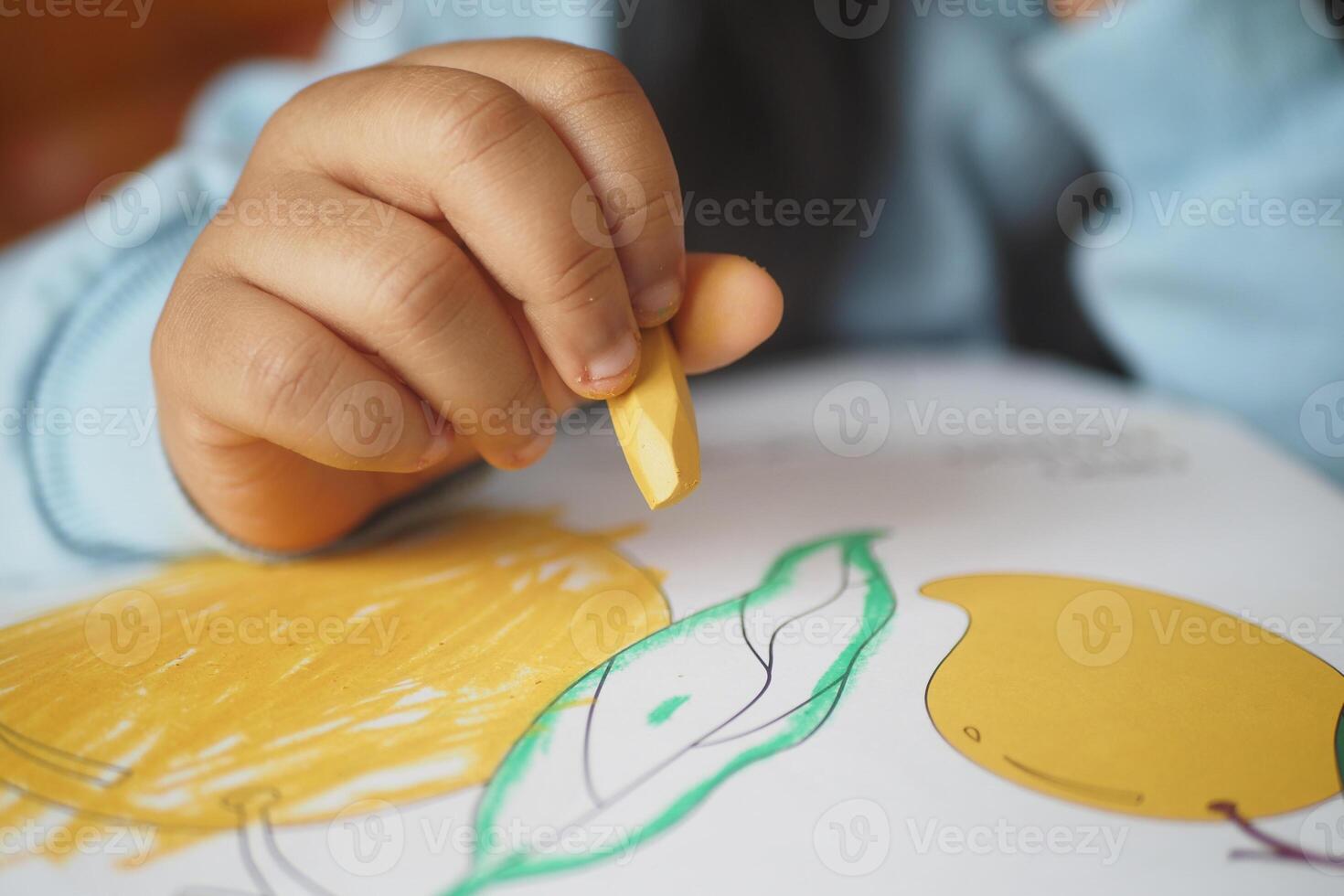A child is happily coloring a lemon illustration using a vibrant crayon photo