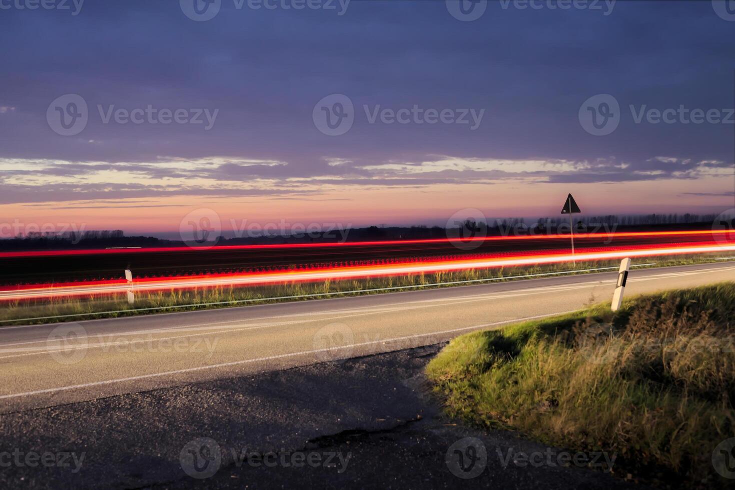 Sunset over a federal road - Bundesstrasse - near Greifswald, Mecklenburg-Vorpommern, Germany. Long exposure makes the movement of car lights visible. photo