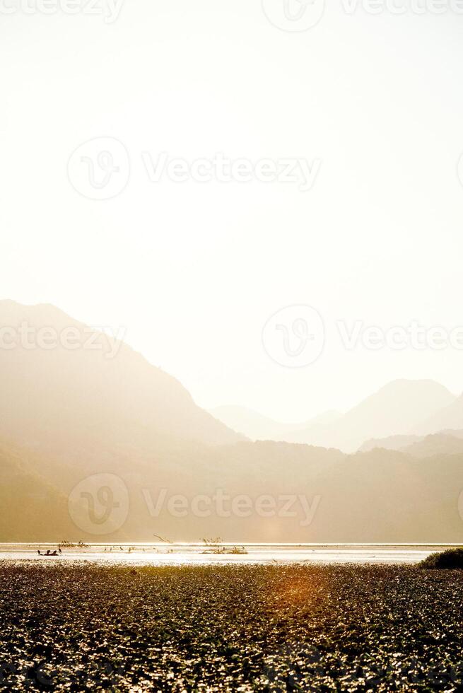 Landscape of blue deep lake in light of sun in daytime, clouds in sky, mountains flow photo