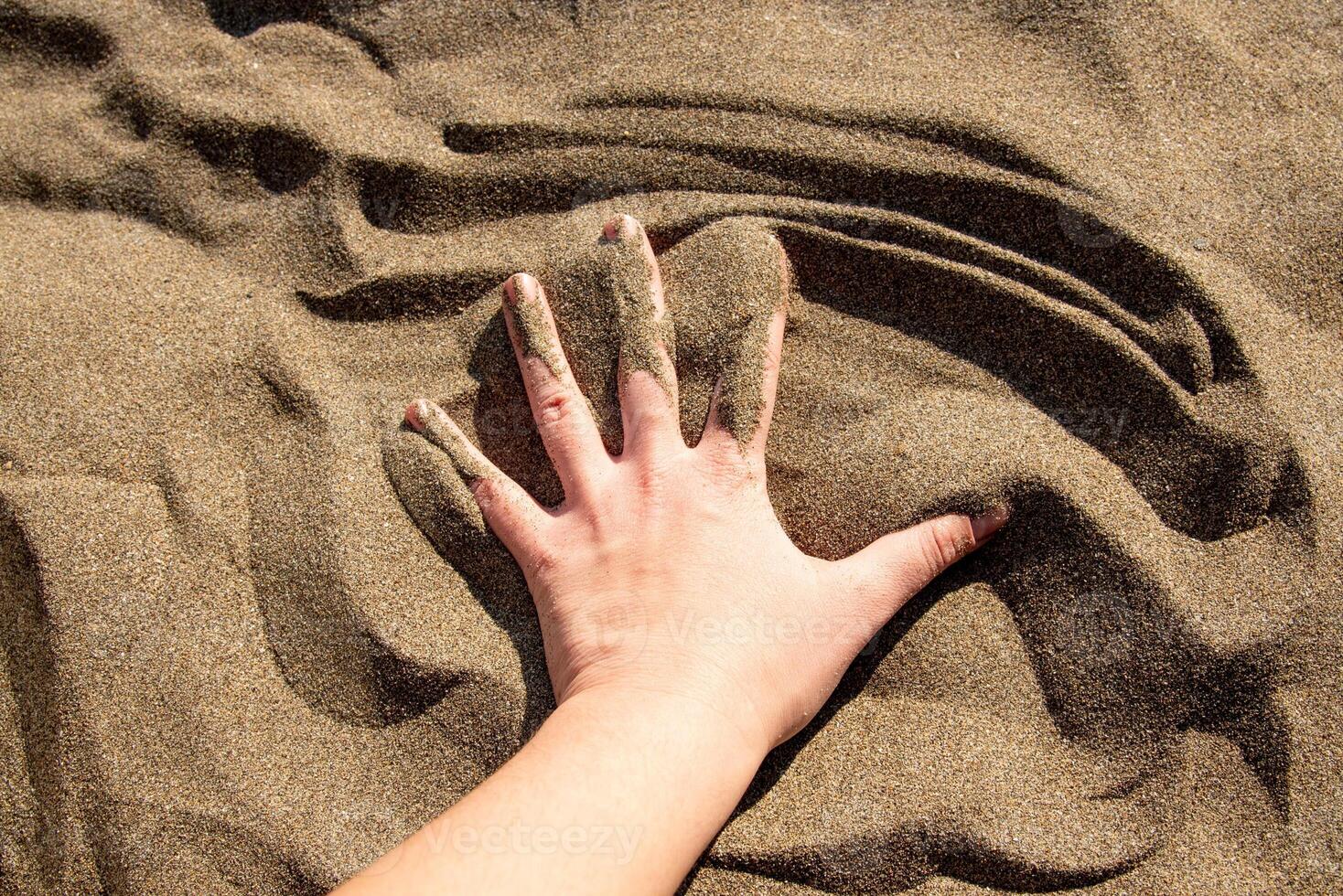 Sandy yellow beach with sea in background cute, hand touches sand photo