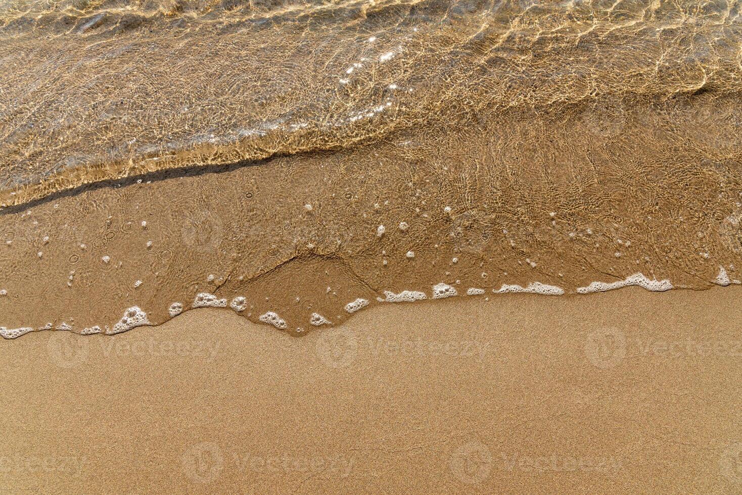 Sandy yellow beach with cute sea in background, wave ocean in sand photo