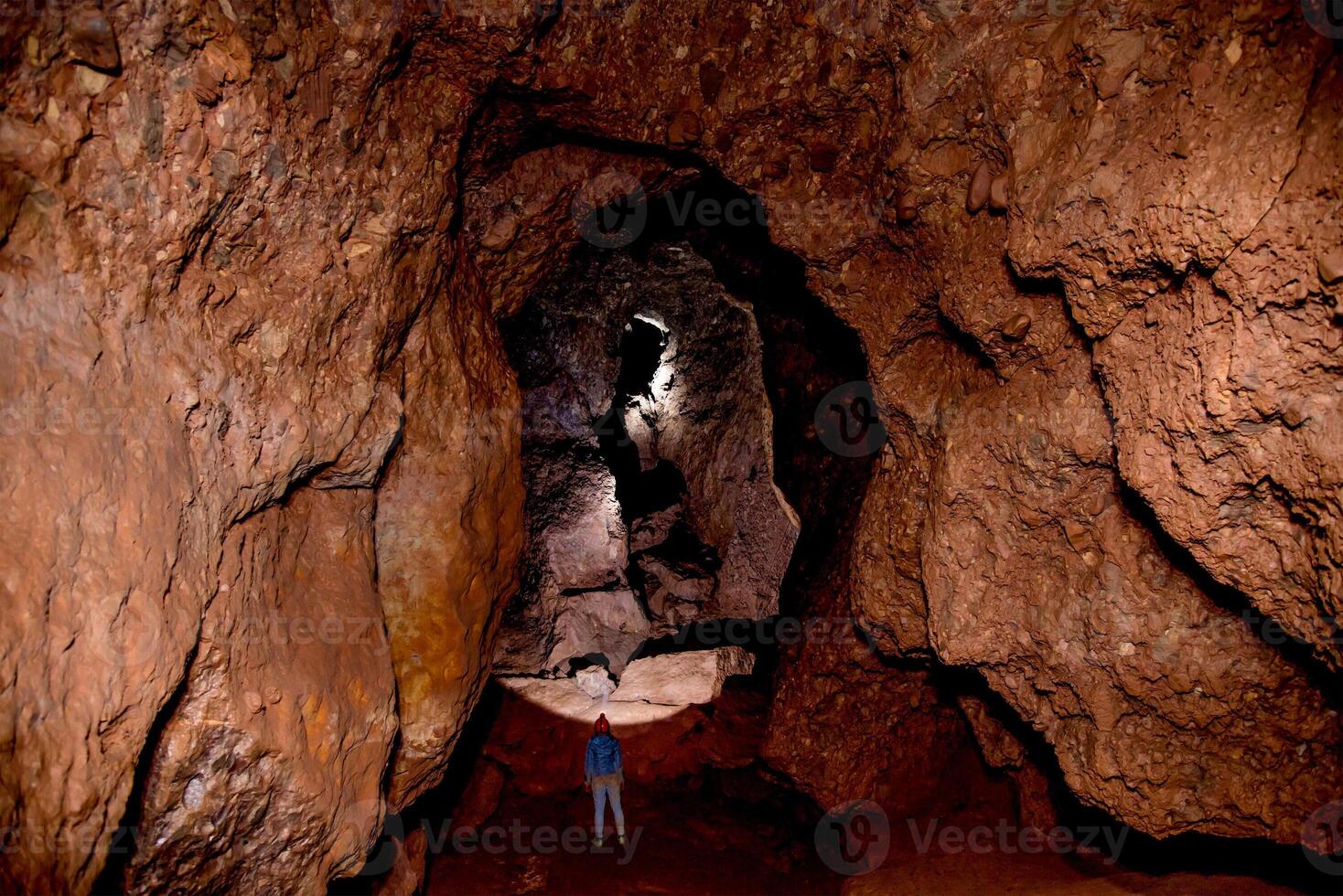 Speleologist explores an underground journey cave, geologist studies hole rock mountain photo