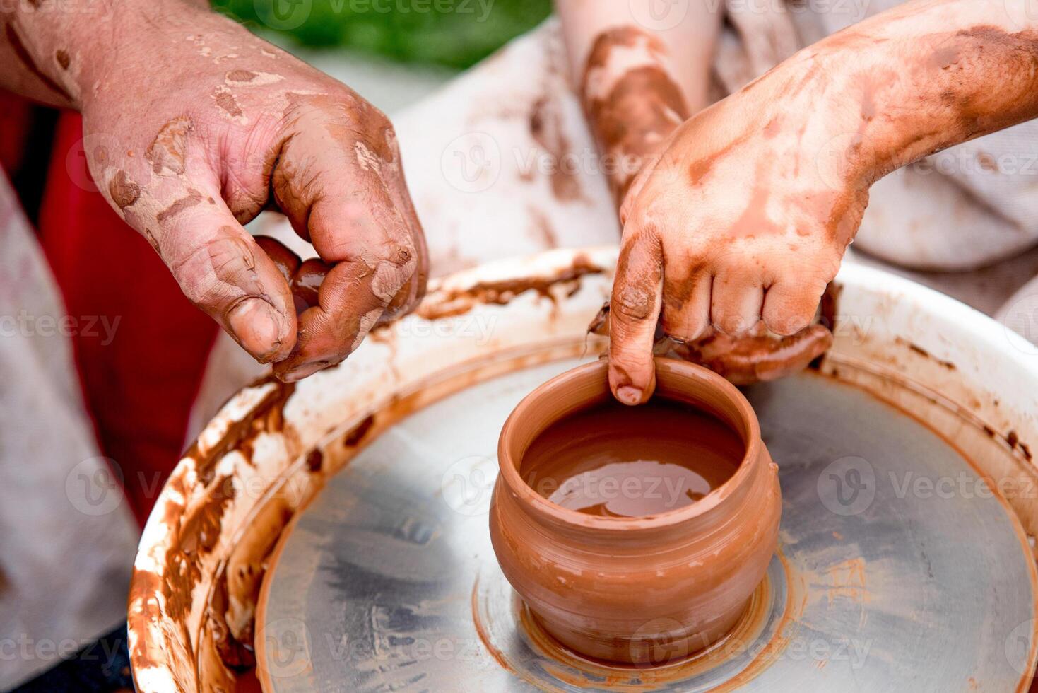 Potter sculpts mug from clay, nice close up dirty hands create vase on ceramist wheel photo