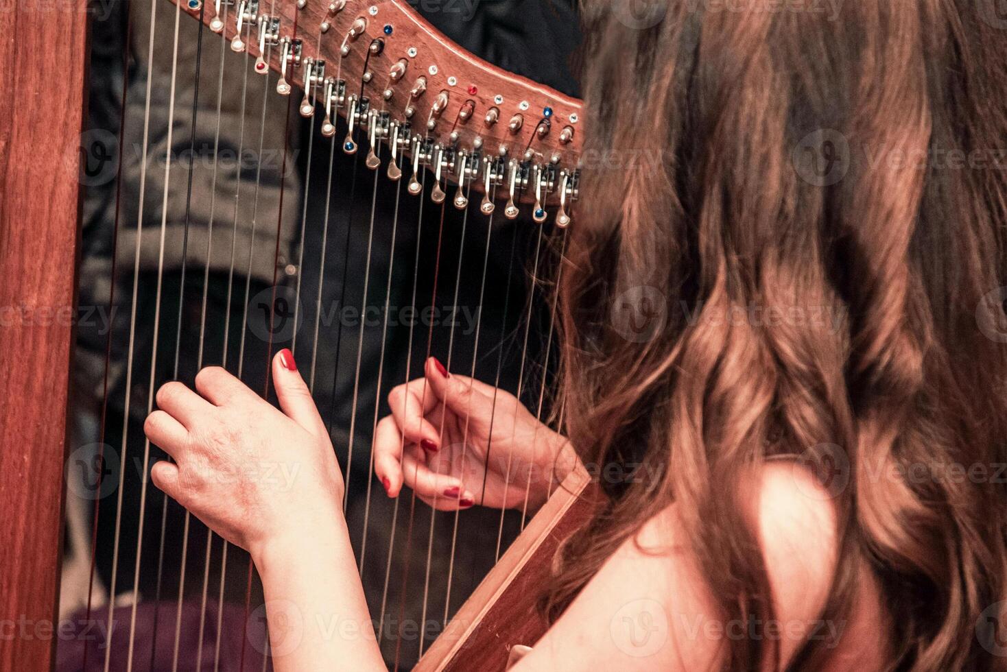 Woman play strings harp nice, musician harper performs at concert in nightclub bar photo